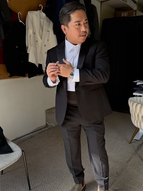 Client adjusting a black custom suit jacket in the shop